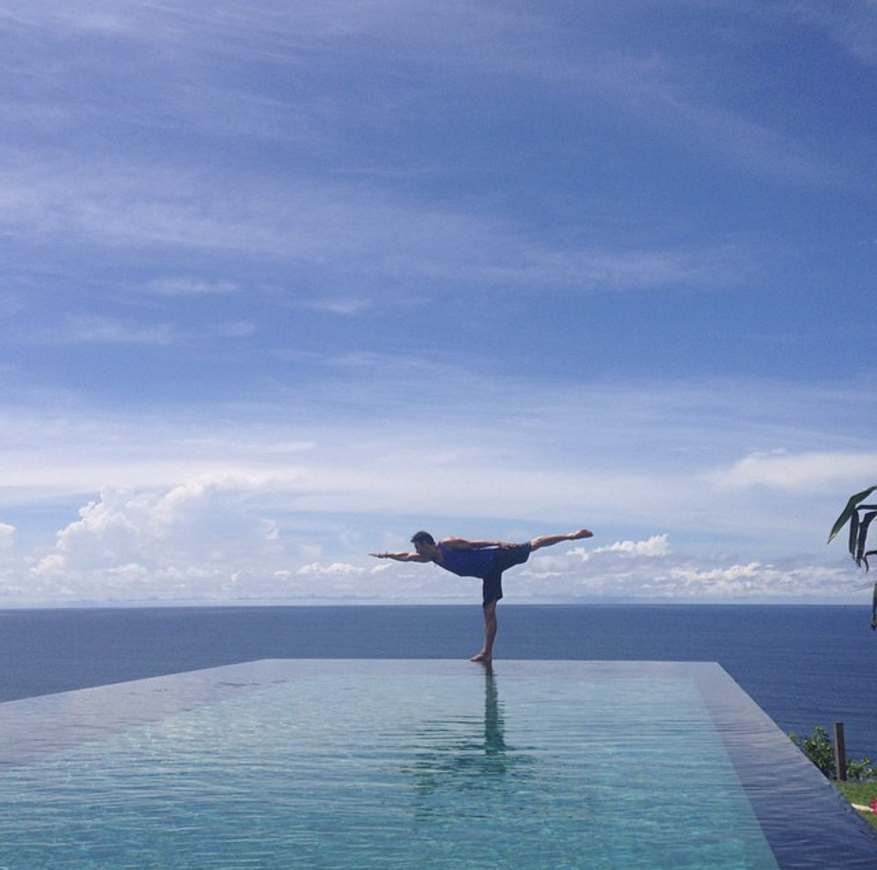Yoga balance on infinity pool overlooking the ocean